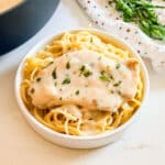 A plate of tarragon chicken over spaghetti.