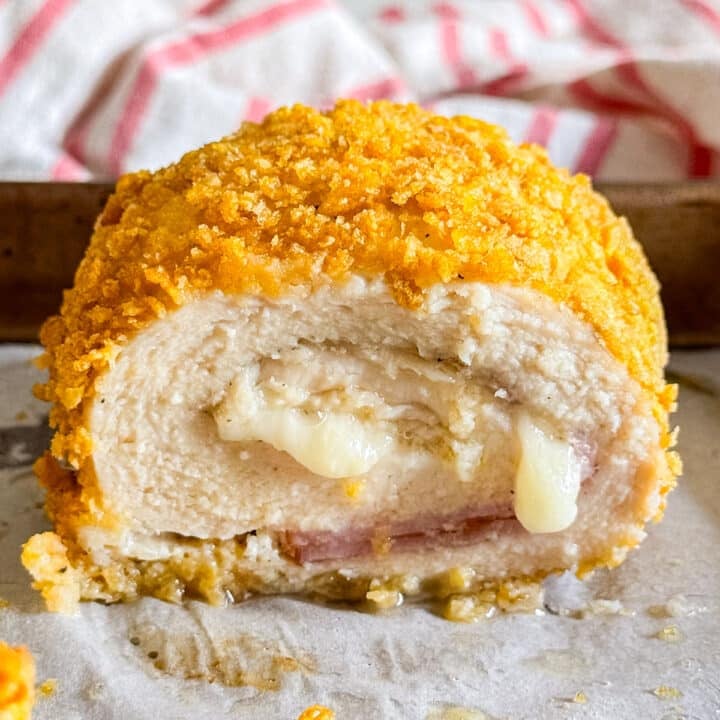 A close up of a chicken cordon bleu cut in half revealing the perfectly cooked chicken, sliced ham and melted Swiss cheese dripping out.