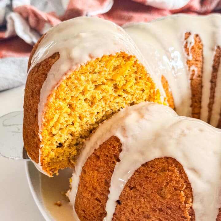 A slice of pumpkin cake being pulled out of the whole bundt cake.