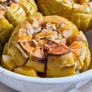A close up of a bloomin' baked apple and oats in a pan.