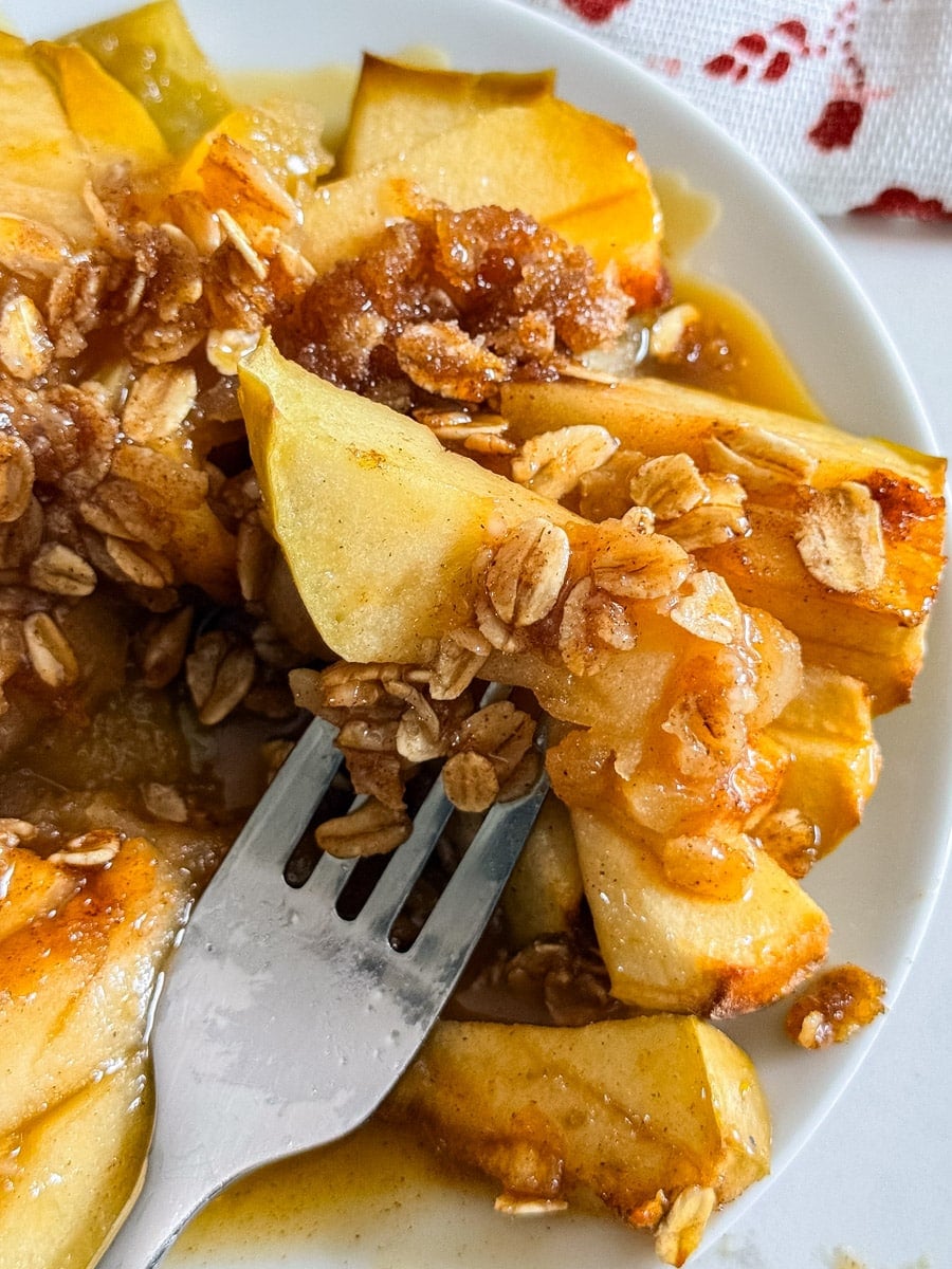 A close up of a bite of baked apple on a fork.