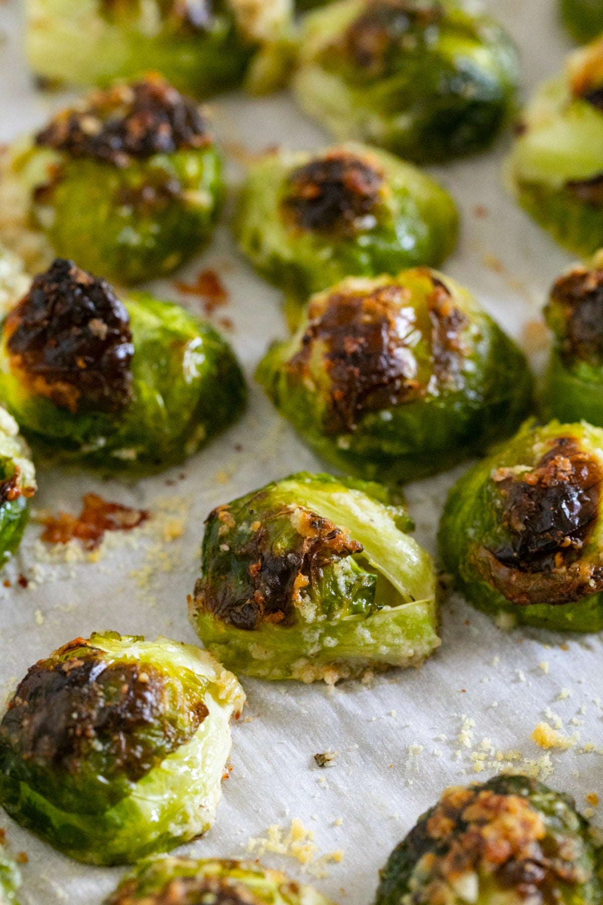 A close up of roasted Brussels Sprouts on a lined sheet pan.